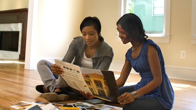 Two women sitting on the floor reviewing design magazines