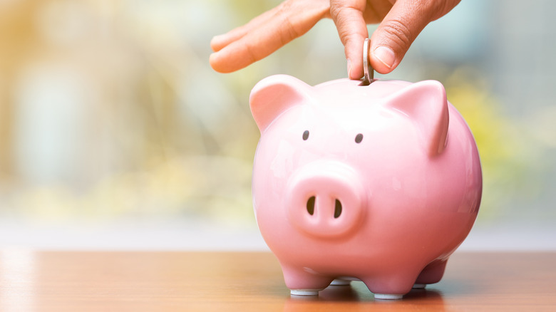 hand putting a coin into piggy bank