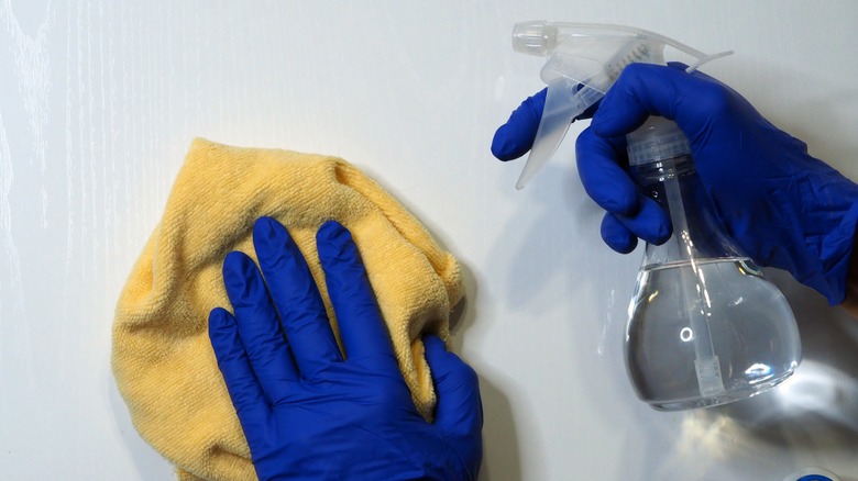 Hands in rubber gloves cleaning with white vinegar
