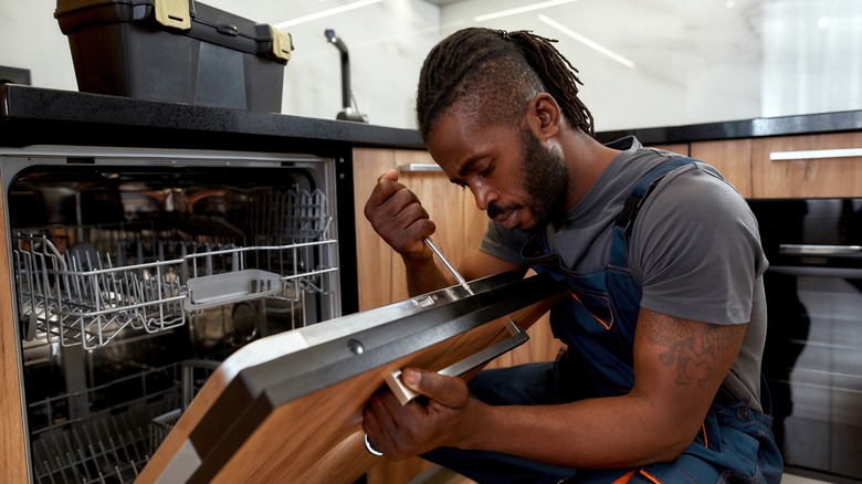 man repairing a dishwasher