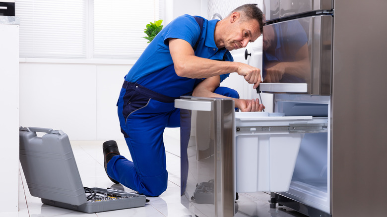 man repairing refrigerator