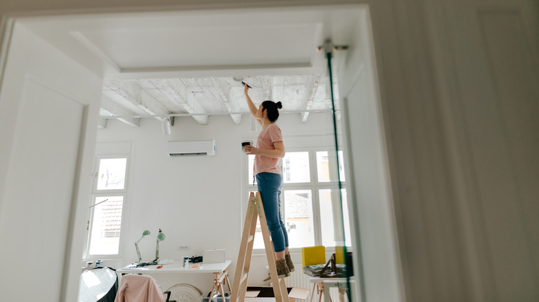 Person on ladder painting ceiling