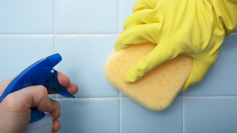 person cleaning shower tiles