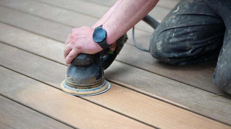 Person using a sander to sand wood flooring