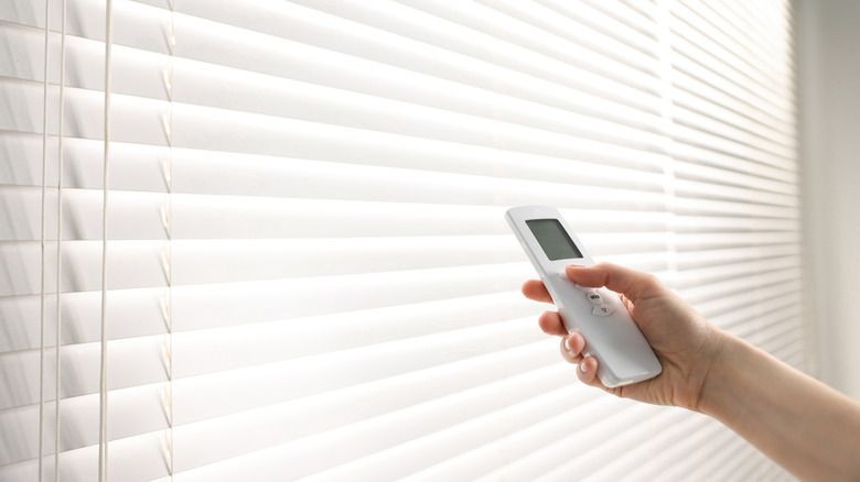 Person opening motorized blinds with remote control