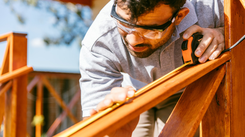 Man measuring the railing of his deck.