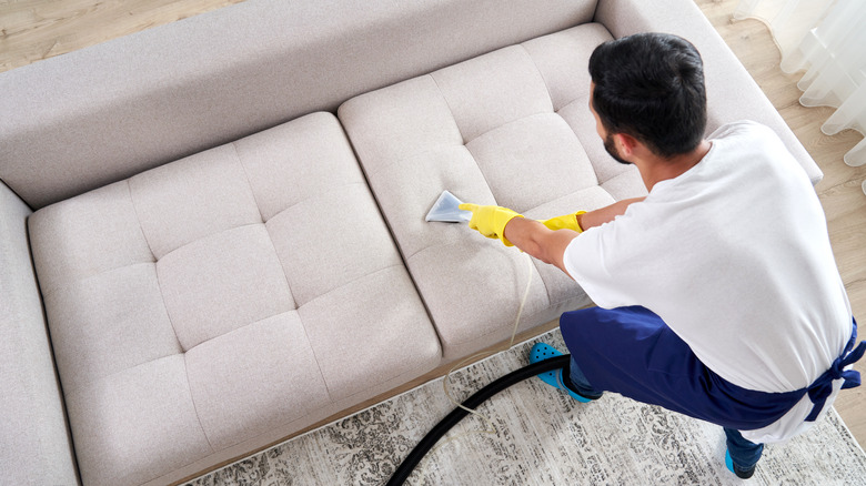 man vacuuming couch