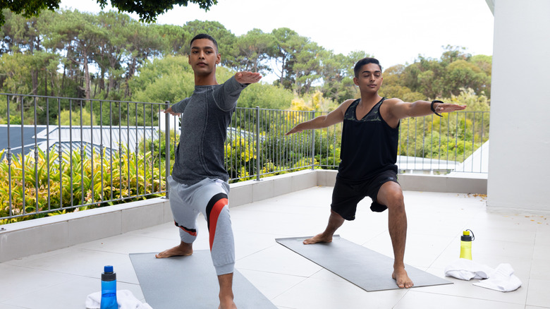 men doing yoga on balcony