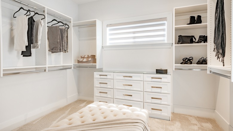 bright walk-in closet with bench