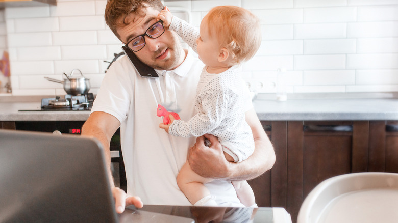 man holding baby and working