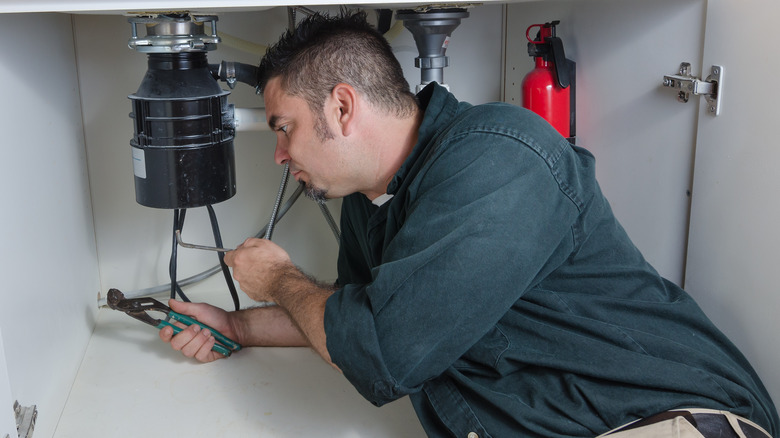 man repairing garbage disposal