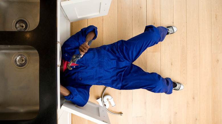 plumber working under sink