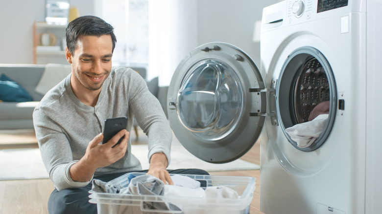 man putting dirty laundry in front-loading washer