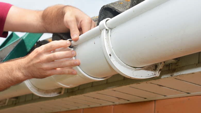 man screwing a roof gutter