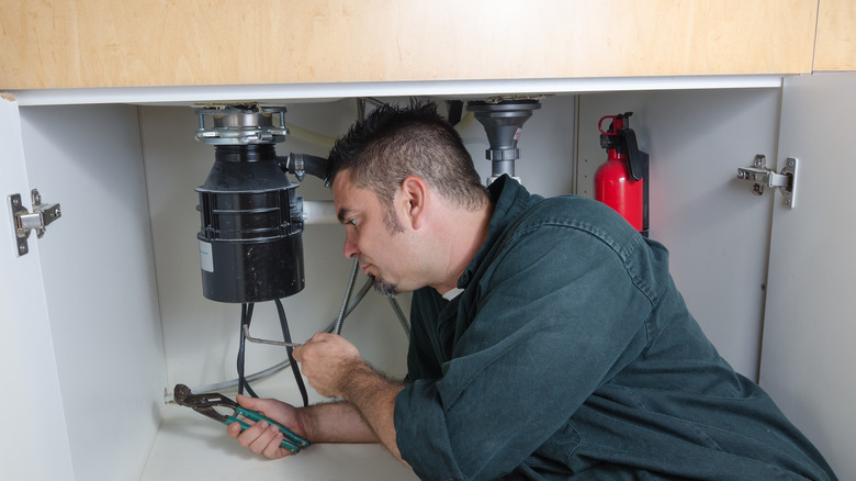 Plumber installing garbage disposal