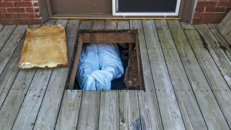 worker crawing into crawl space