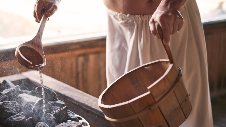 Man pouring water over sauna stones