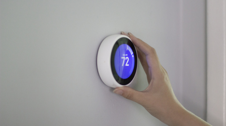 Woman adjusts smart thermostat