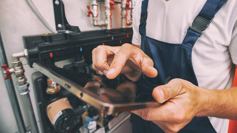 technician checking heating system with tablet