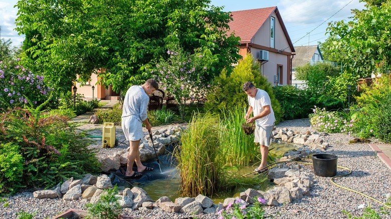 two men cleaning backyard pond