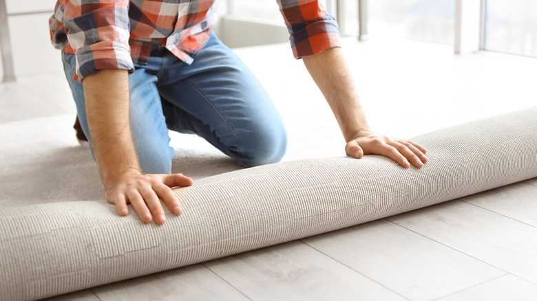 Installer laying carpet across floor