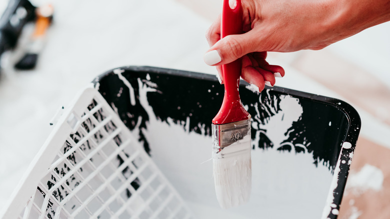 Woman's hand dipping paint brush