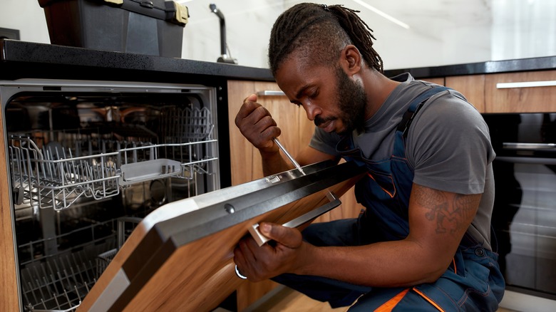 worker installing dishwasher in modern kitchen