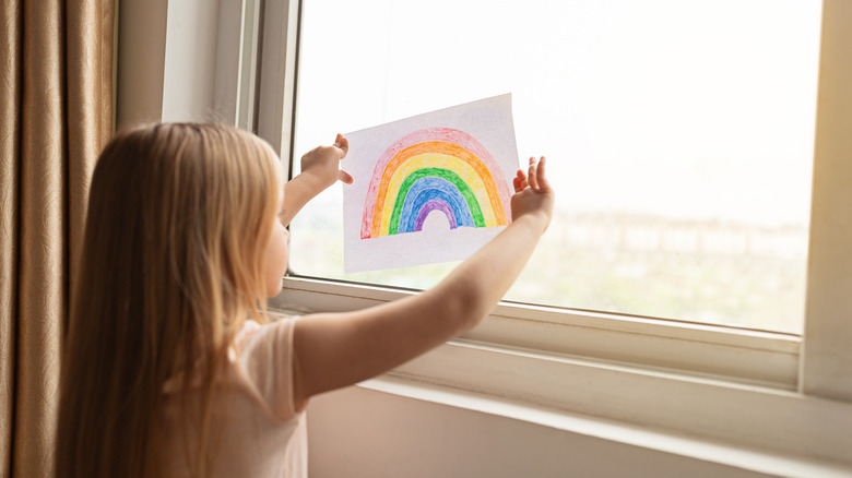 kid putting rainbow in window