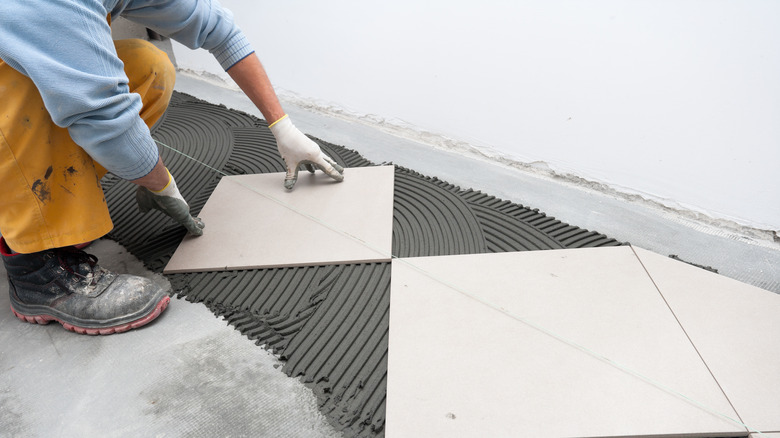 Person installing tile on mortar