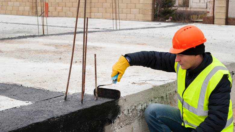 worker waterproofing the foundation