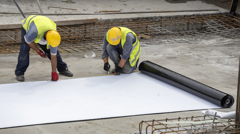 workers waterproofing at construction site