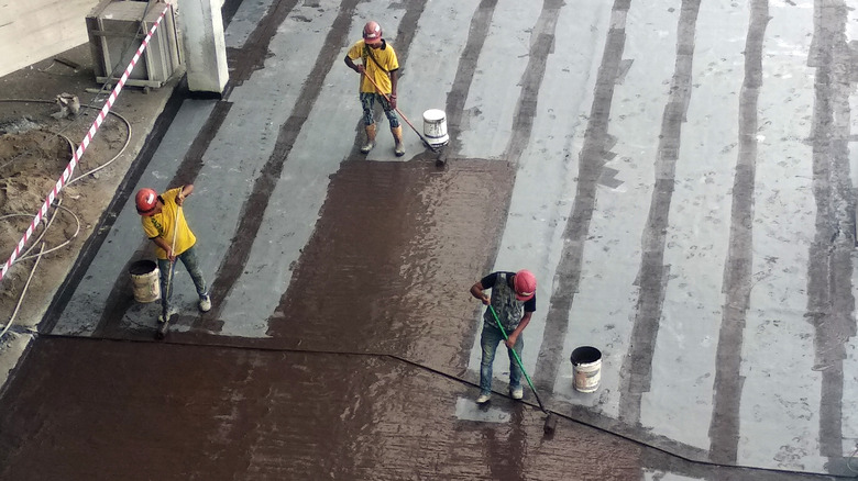 workers waterproofing a concrete slab