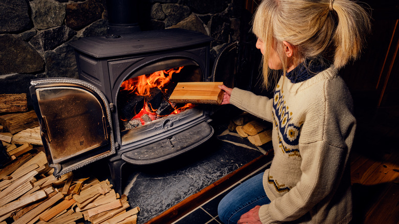 Adding firewood to wood stove