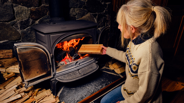 Woman putting log wood stove