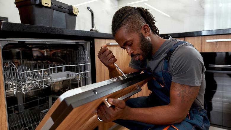 man installing stainless steel dishwasher