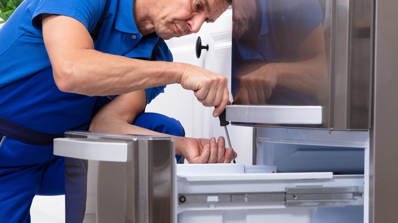 man installing stainless steel freezer