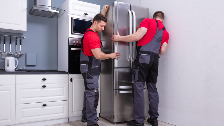 men installing stainless steel refrigerator