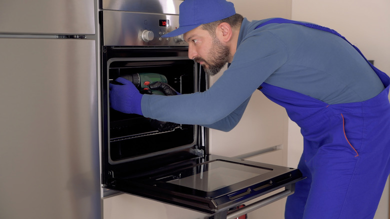 man installing wall oven