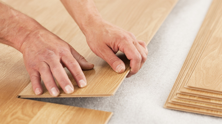 person installing laminate flooring planks