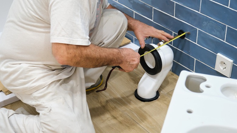 plumber measuring toilet rough-in