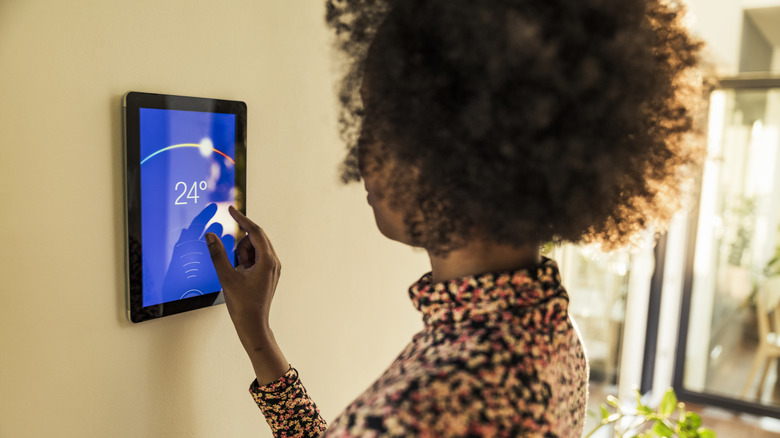 Woman programming smart thermostat