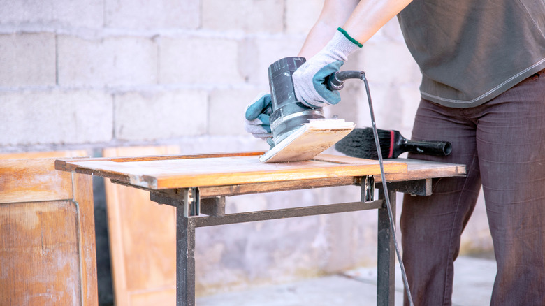 woman sanding a cabinet for refinishing