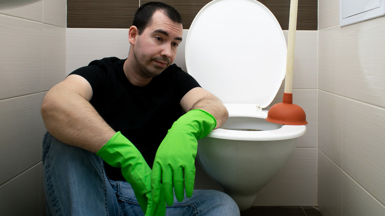 Disgruntled man sitting by toilet