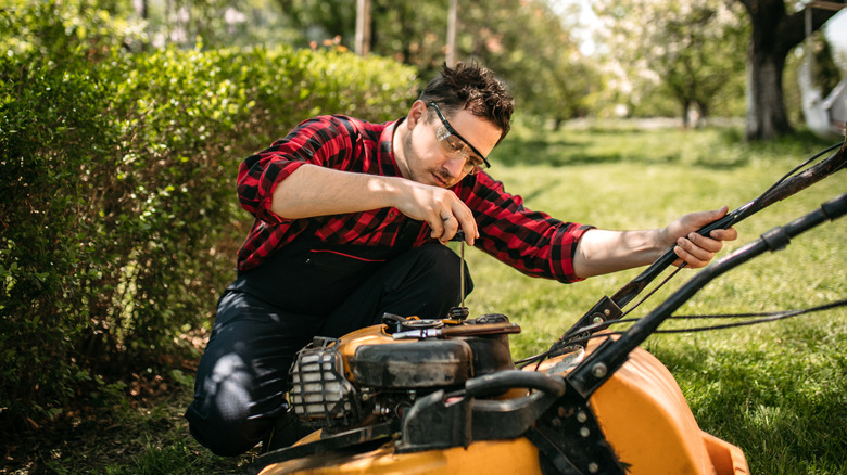 man checking lawnmower motor 