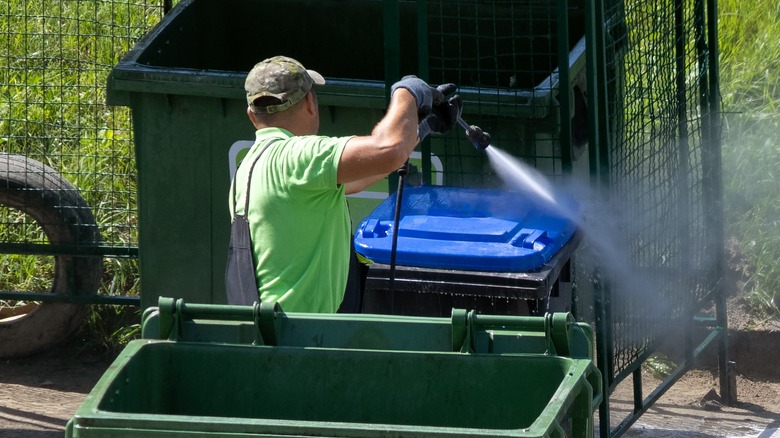 Man spraying garbage can