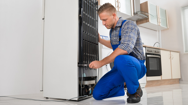 man working on refrigerator coils