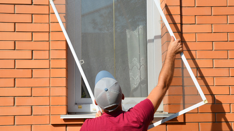 Man removing screen from window