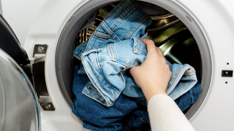 Woman putting jeans in washer