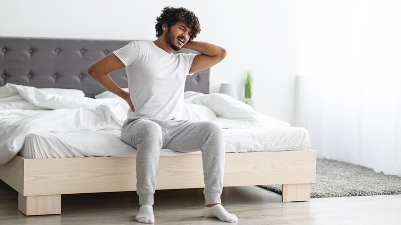 man on mattress holding back