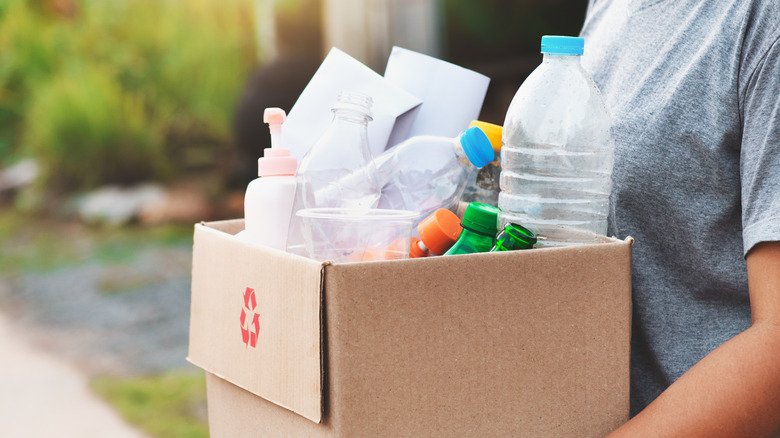 woman carrying box of bottles